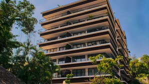 Un immeuble à plusieurs étages doté de balcons, dont certains sont ornés de plantes.