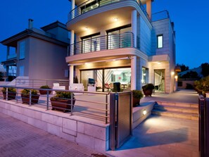 A modern two-story building with a balcony, outdoor seating, and a gated entrance. - Bohemi, luxury seafront villa (Santa Margalida - Can Picafort/Son Serra Marina)