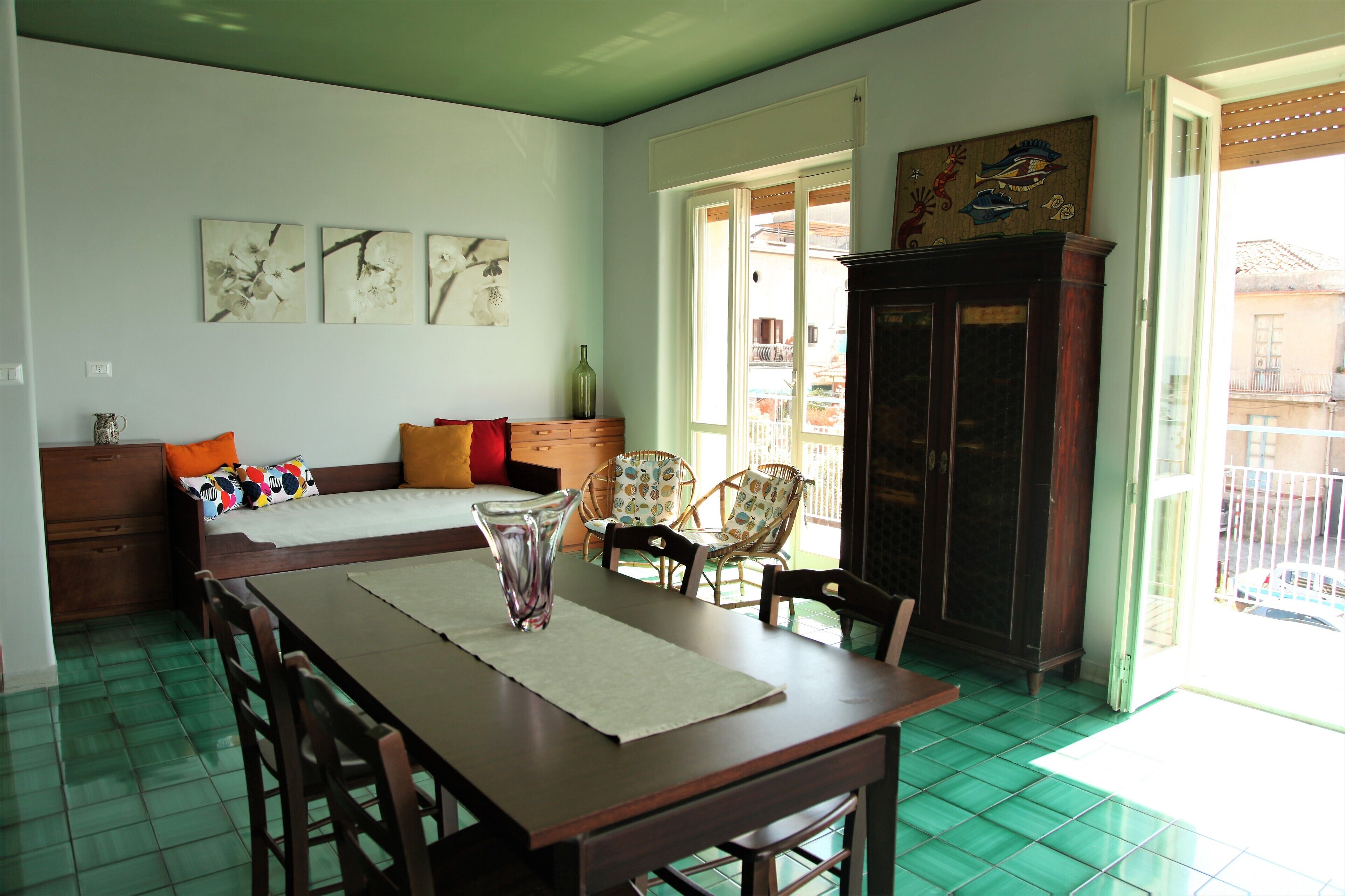 Un comedor con una mesa, sillas y un banco. Hay un armario y una ventana con vistas al exterior.