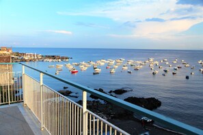 Une vue sur la côte, avec une marina remplie de bateaux, une côte rocheuse et, au loin, un bâtiment surmonté d’un toit rouge.