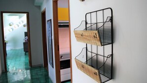A hallway with a tiled floor and a door leading to another room. There is a wall-mounted rack with numbered compartments.