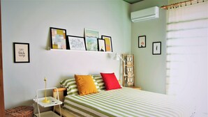 A bedroom with a bed, bedside tables, a lamp, a basket, and wall art.