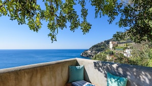 A balcony with a view of the sea, a cushion, and a book.