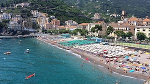 A coastal town with a beach, buildings, and a mountainous backdrop.