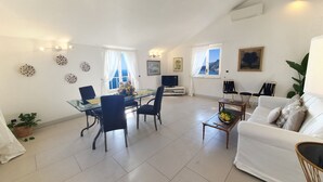 A spacious living area with a dining table, chairs, a sofa, and a TV.