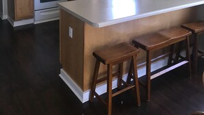 Una cocina con armarios de madera, estufa blanca, microondas e una isla grande con taburetes.