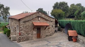 A stone building with a tiled roof, a wooden door, and a small porch area. - Stone Cottage The Compostelana (Curtis)