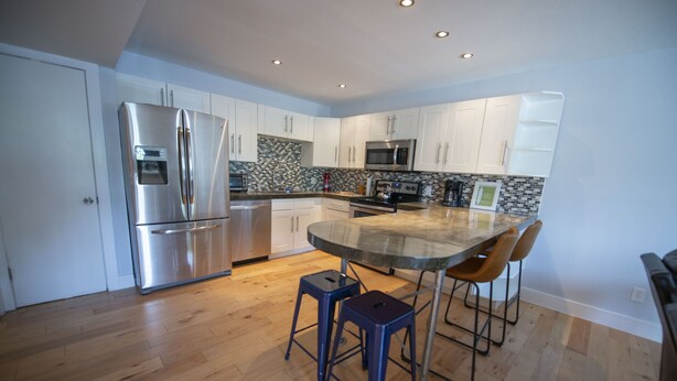 A modern kitchen with stainless steel appliances, white cabinets, and a wooden floor. - Shoal Creek Greenbelt (Austin)