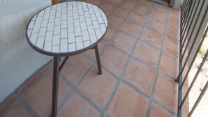 A small patio area with a tiled table and chairs, a sliding glass door, and a television in the background. - Shoal Creek Greenbelt (Austin)