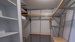 A storage room with metal shelving, wooden flooring, and a ceiling light. - Shoal Creek Greenbelt (Austin)