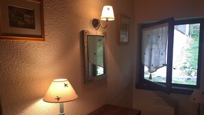 A room with a wooden table, a lamp, a mirror, and a window with a view of the outdoors. - La Tournette apartment Les Maisons des Bois (Manigod)