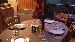 A round dining table with a festive tablecloth, set with plates, glasses, and cutlery. - La Tournette apartment Les Maisons des Bois (Manigod)