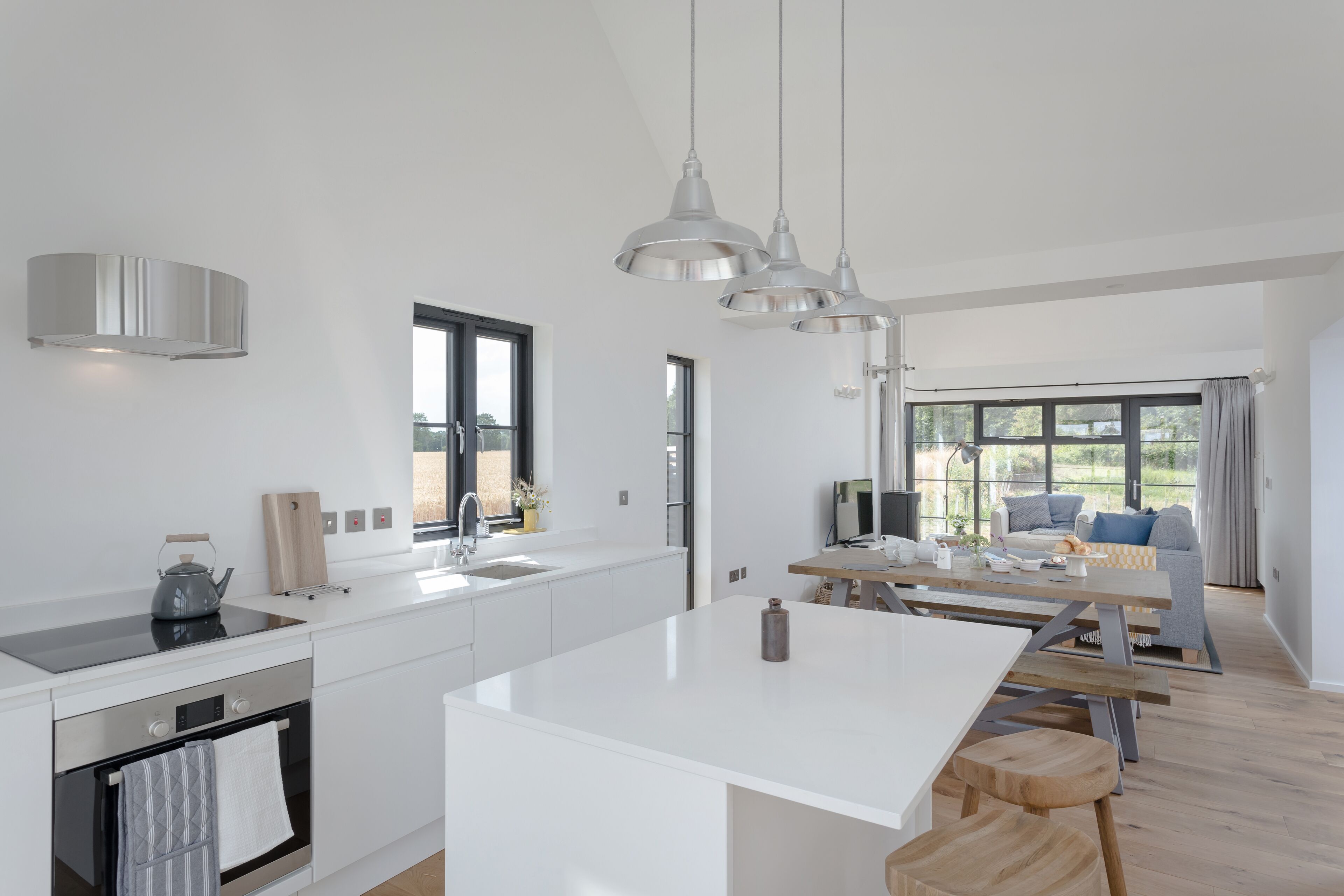 A modern kitchen with white cabinetry, a central island, and pendant lighting.