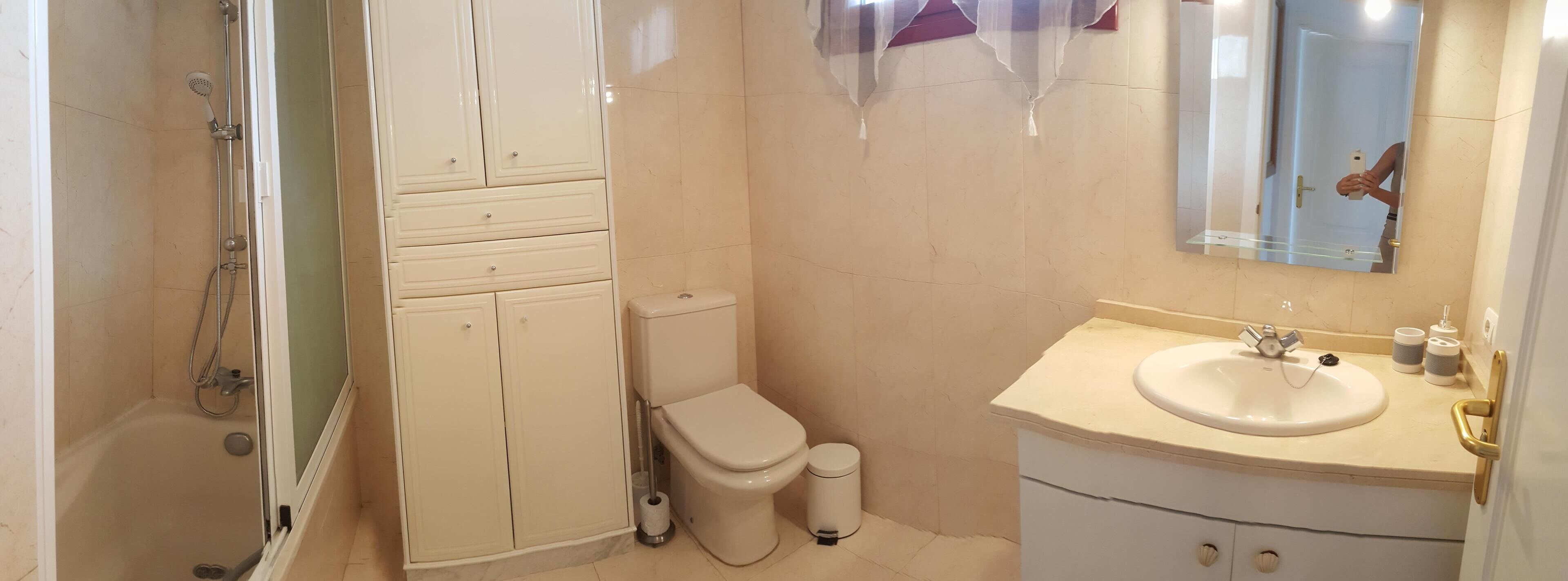 A bathroom with a shower, toilet, and sink.