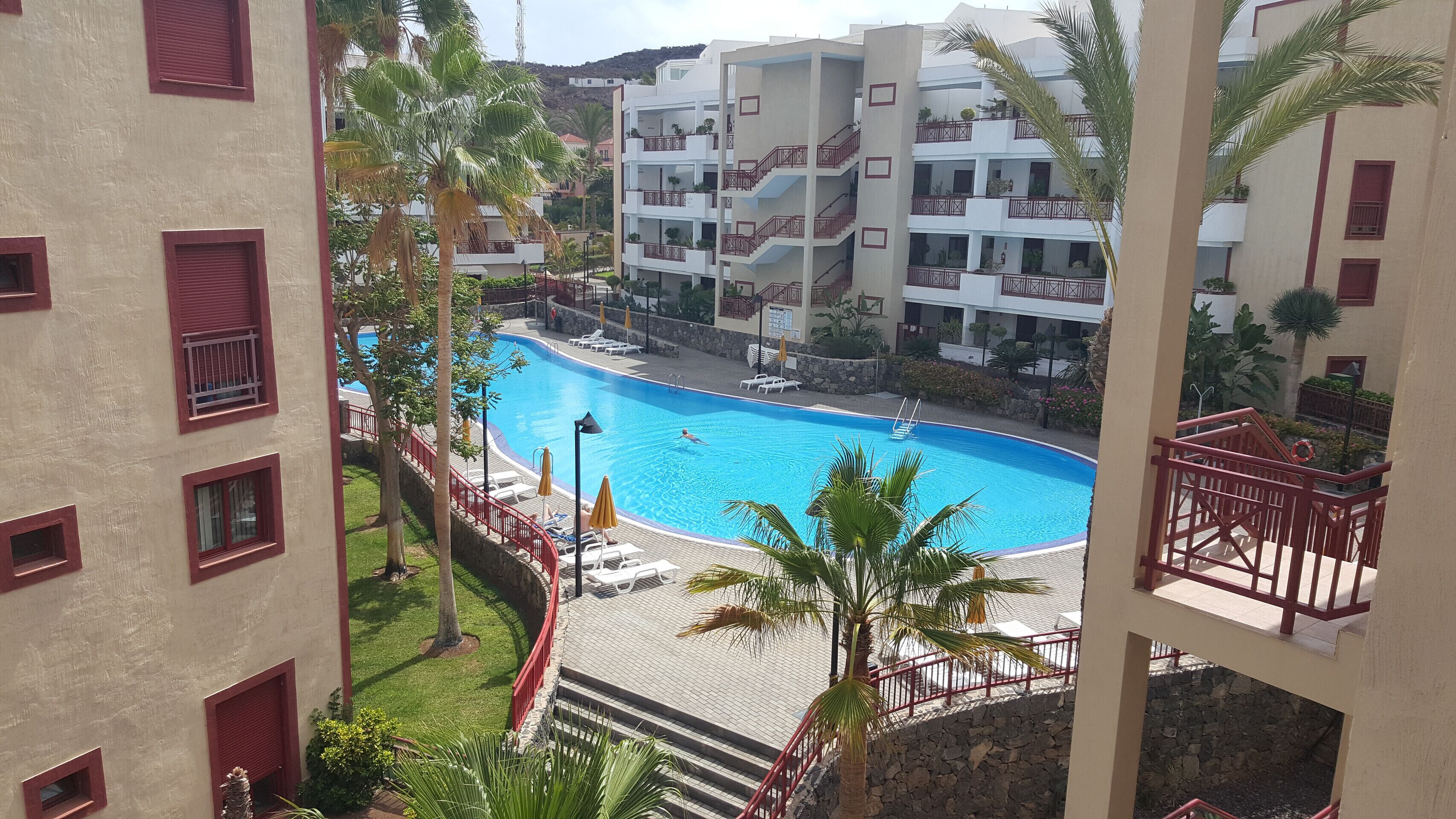 Un hôtel doté d’une piscine, de plusieurs balcons et offrant une vue sur les bâtiments environnants.
