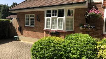 A brick house with white shutters, a tiled roof, and a brick pathway leading to the entrance.