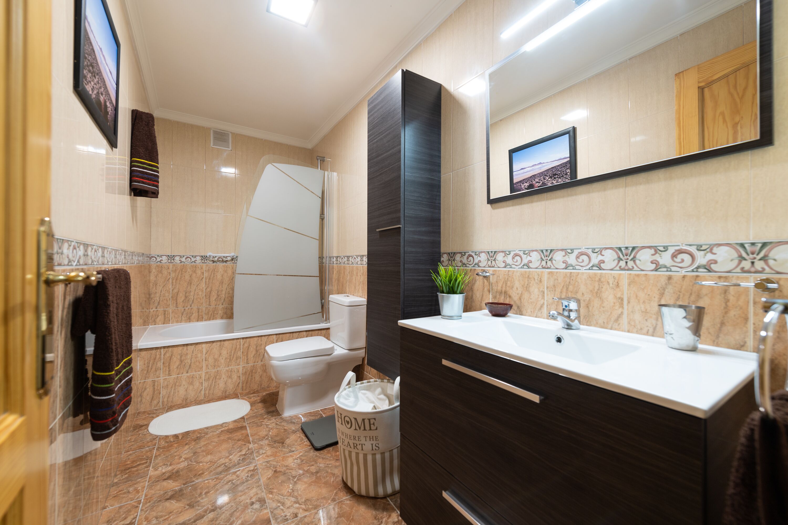 A modern bathroom with a bathtub, toilet, sink, and a mirror.