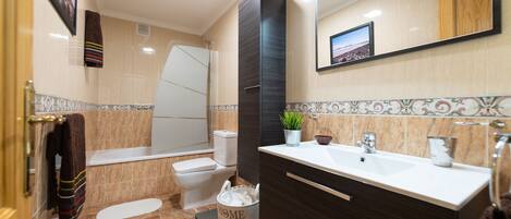 A modern bathroom with a bathtub, toilet, sink, and a mirror.