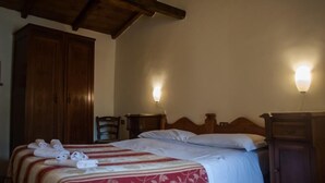 Ein Hotelzimmer mit Holzboden, einem Bett mit rot-weiß gestreifter Bettdecke, zwei Nachttischen und zwei Wandleuchten.