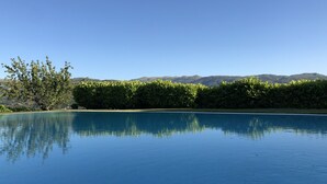 Ein klares, blaues Schwimmbecken, das Bäume und Berge im Hintergrund spiegelt.