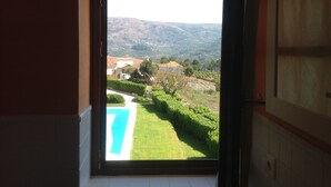 A view from a window with a clear sky, a swimming pool, and a landscape with buildings and hills. - House of Steps - Santa Marinha do Zêzere (Baiao)