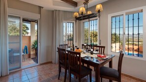 A dining area with a table set for four, surrounded by chairs, with a view of the outdoors through large windows. - Cubo's La Casa Grande / Jacuzzi / pool / air conditioning / garden (Cártama)