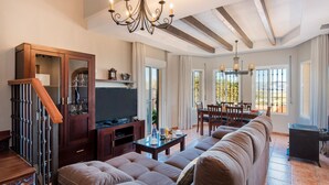 A spacious living room with a large sectional sofa, a television, and a dining area with a table and chairs. - Cubo's La Casa Grande / Jacuzzi / pool / air conditioning / garden (Cártama)