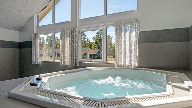 A modern bathroom with a large bathtub, large windows, and a view of a house outside. - Gorgeous home in Frederiksværk (Frederiksværk)
