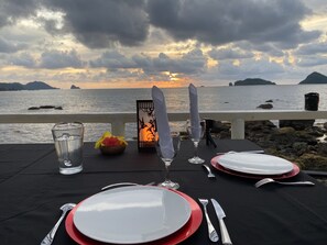 Ein Tisch für zwei Personen mit Blick auf Meer und Berge bei Sonnenuntergang.