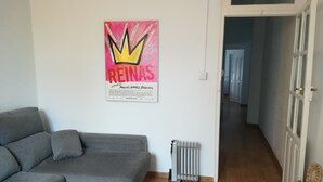 Ett vardagsrum med en grå soffa, ett litet bord och ett element. En affisch hänger på väggen.