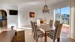 Un comedor con una mesa y sillas, un candelabro, una chimenea y un ventanal con vistas.