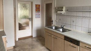 A kitchen with a sink, dishwasher, and tiled backsplash. - Modern apartment in Dresden (Dresden)