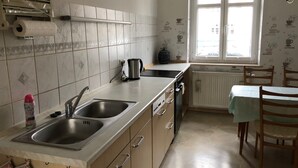 A kitchen with a double sink, a coffee maker, a radiator, and a window with a view. - Modern apartment in Dresden (Dresden)