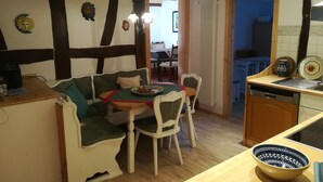 Tunnelmallinen ruokailutila, jossa on puinen pöytä, tuoleja ja sohva. Pöydällä on lautanen täynnä ruokaa.
