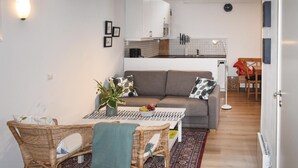 A compact living space with a sofa, dining table, wicker chairs, a small kitchen area, and a view of the outdoors. - Awesome home in Löttorp with kitchen (Löttorp)