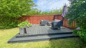 A wooden deck with outdoor furniture, surrounded by a red fence and lush greenery. - Awesome home in Löttorp with kitchen (Löttorp)