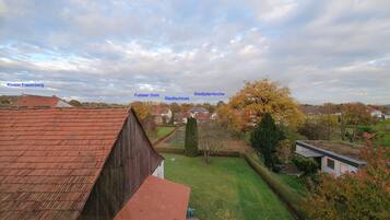 Blick aus einem Fenster auf einen Innenhof mit einem roten Bauernhofdach, einer Kirche und einem Rathaus.