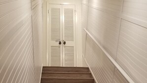 A staircase with wooden steps leading to a white door with louvered shutters.