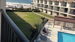 A hotel with a pool, a beach view, and a lawn area.