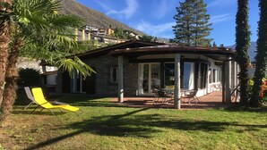 Un espacio de estar al aire libre con techo, una terraza, una silla amarilla y vistas a una montaña.