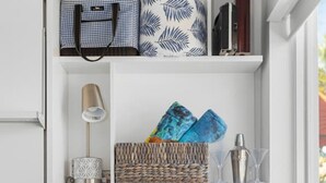 Una sala de estar moderna con un sofá azul, un estante blanco con diversos objetos, y una ventana.