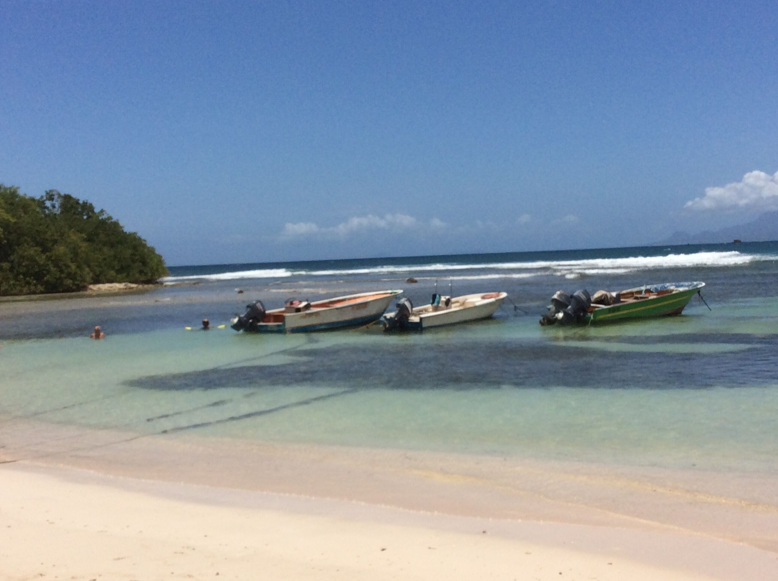 A beach with several boats anchored near the shore.