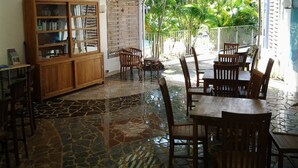 Un patio interior con suelo de baldosas, mobiliario de madera y un toldo a rayas.