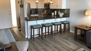 Une cuisine moderne dotée d’un îlot central, de tabourets de bar et d’un coin repas avec une table et des chaises.