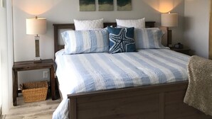 Une chambre à coucher avec un lit en bois, une literie à rayures et trois lampes fixées au mur.