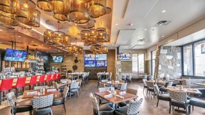 A spacious restaurant with multiple dining areas, a bar, and large windows providing natural light. - Gorgeous Oakwood Vacation Home with Golf Cart! Spotless!!! (Sun Lakes)