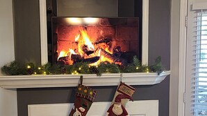 Una chimenea con fuego, calcetines decorativos y un cartel arriba.