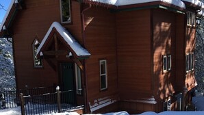 Eine Holzhütte mit einem steilen Dach, umgeben von schneebedeckten Bäumen.