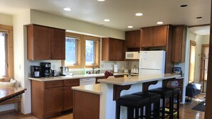 Eine moderne Küche mit Holzausstattung, einer zentralen Kochinsel mit Barhocker, einer Mikrowelle und einem Kühlschrank.