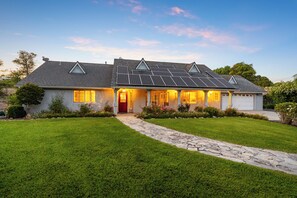 A two-story house with a sloped roof, solar panels, and a well-maintained lawn.